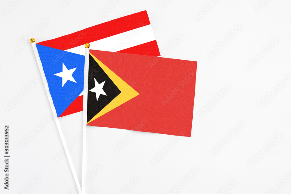 East Timor and Puerto Rico stick flags on white background. High quality fabric, miniature national flag. Peaceful global concept.White floor for copy space. East Timor and Puerto Rico stick flags on white background. High quality fabric, miniature national flag. Peaceful global concept.White floor for copy space.