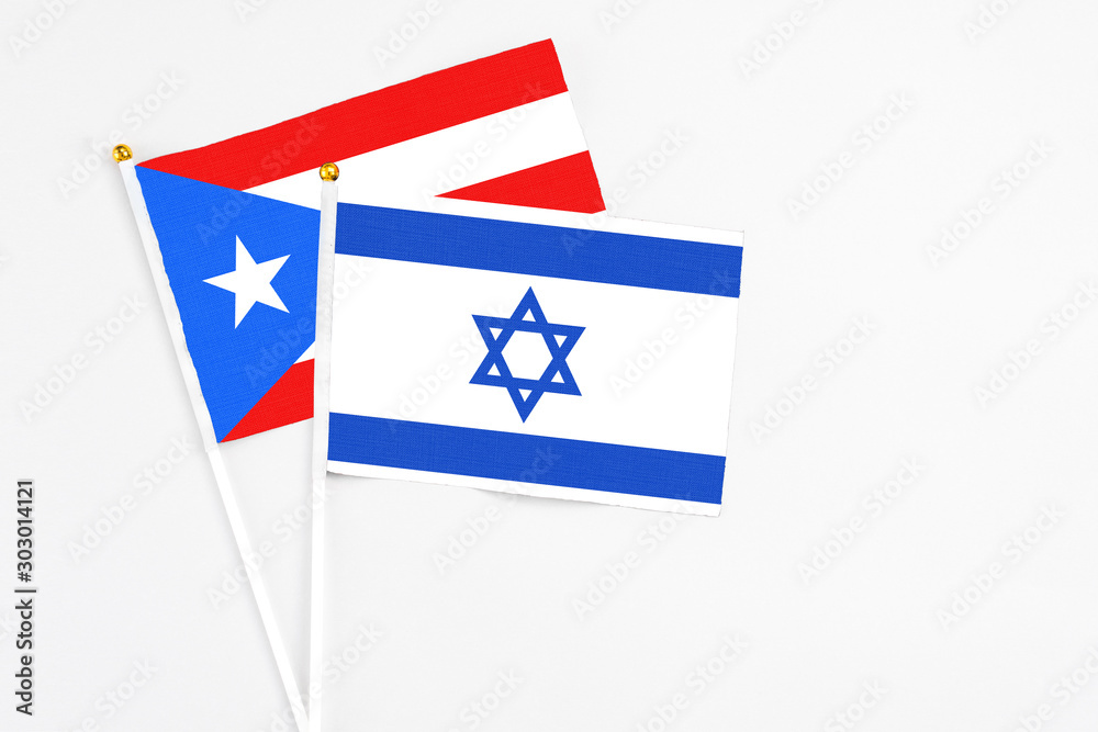 Fototapeta premium Israel and Puerto Rico stick flags on white background. High quality fabric, miniature national flag. Peaceful global concept.White floor for copy space.