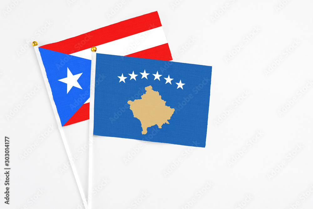 Kosovo and Puerto Rico stick flags on white background. High quality fabric, miniature national flag. Peaceful global concept.White floor for copy space.