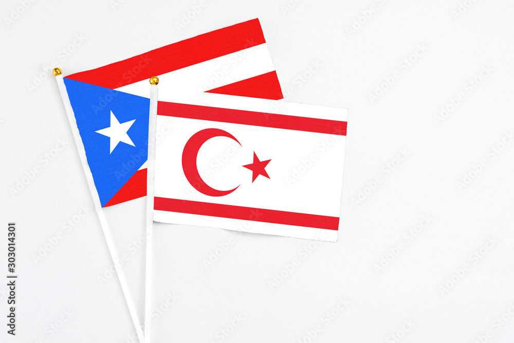 Northern Cyprus and Puerto Rico stick flags on white background. High quality fabric, miniature national flag. Peaceful global concept.White floor for copy space.
