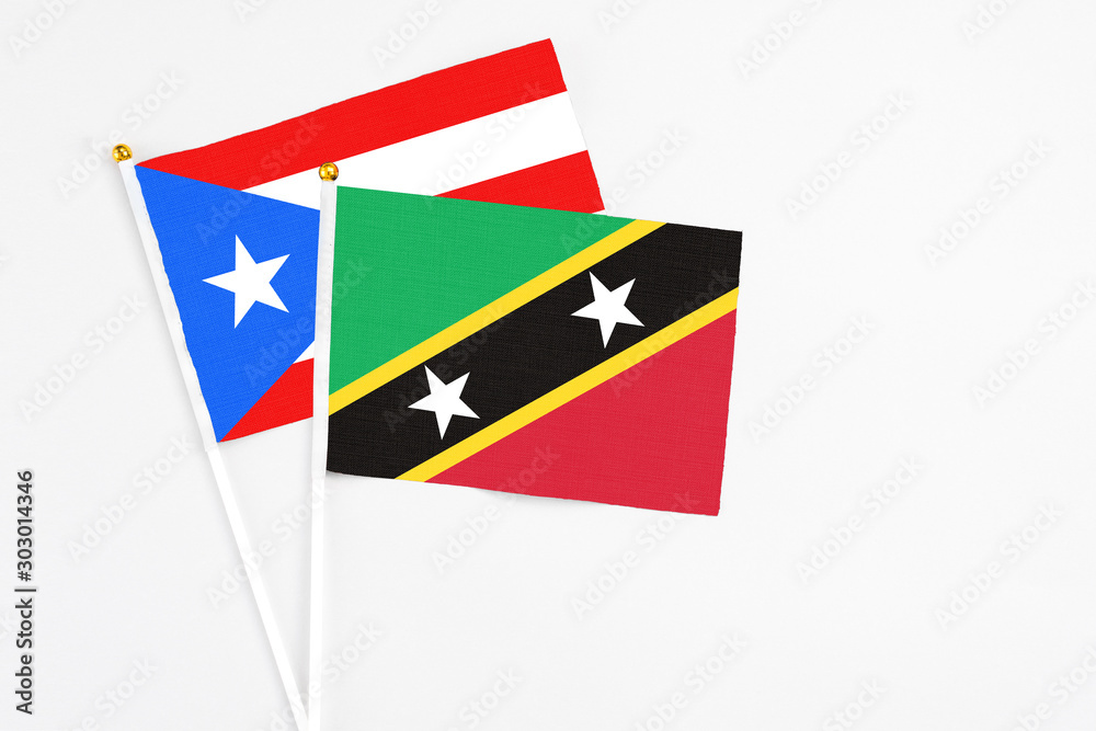 Saint Kitts And Nevis and Puerto Rico stick flags on white background. High quality fabric, miniature national flag. Peaceful global concept.White floor for copy space. Saint Kitts And Nevis and Puerto Rico stick flags on white background. High quality fabric, miniature national flag. Peaceful global concept.White floor for copy space.