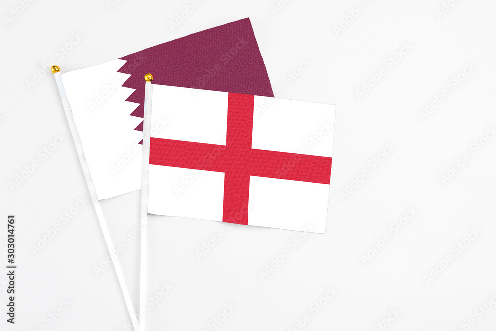 England and Qatar stick flags on white background. High quality fabric, miniature national flag. Peaceful global concept.White floor for copy space.