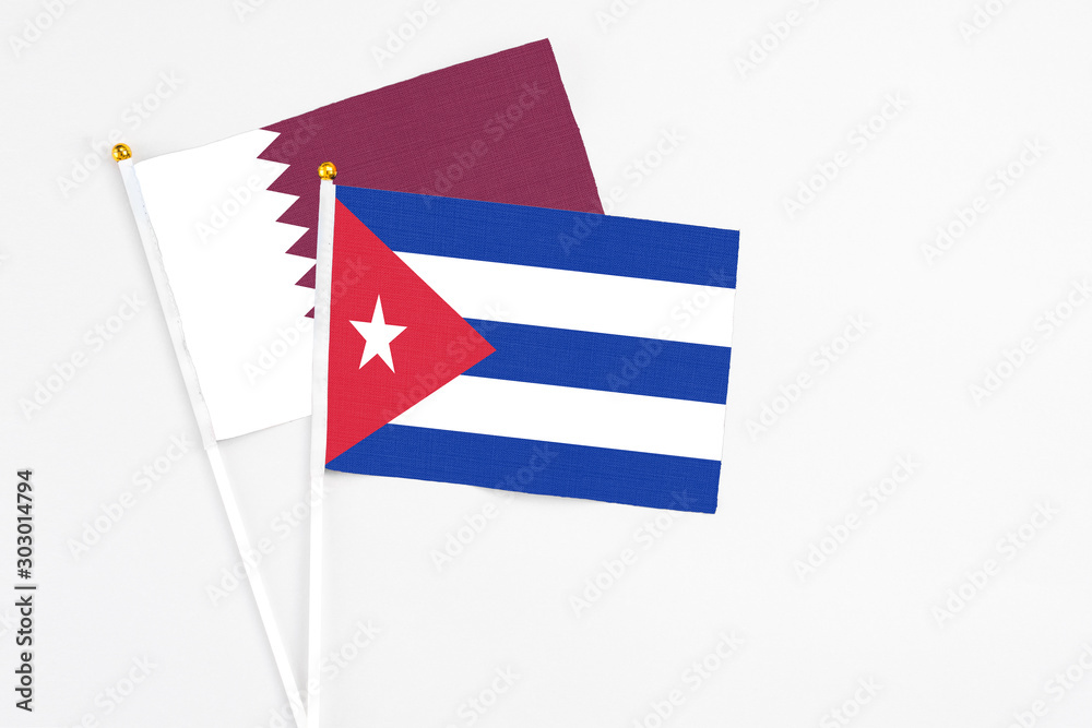 Cuba and Qatar stick flags on white background. High quality fabric, miniature national flag. Peaceful global concept.White floor for copy space.