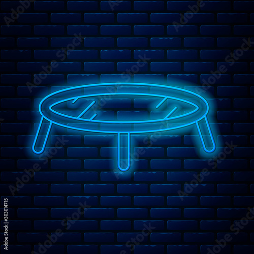 Glowing neon line Jumping trampoline icon isolated on brick wall background. Vector Illustration