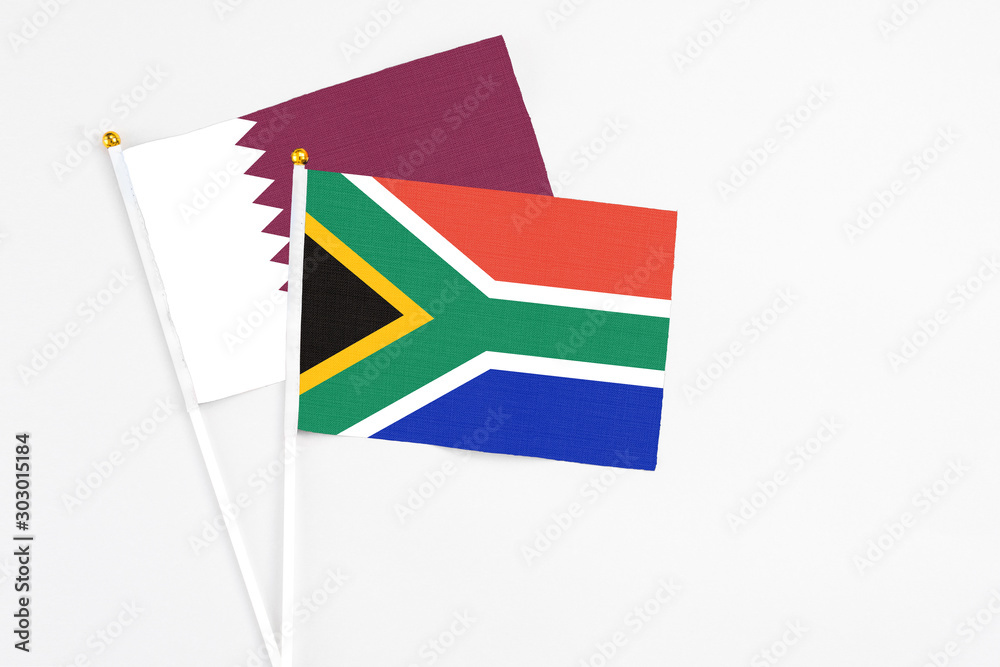 Fototapeta premium South Africa and Qatar stick flags on white background. High quality fabric, miniature national flag. Peaceful global concept.White floor for copy space.