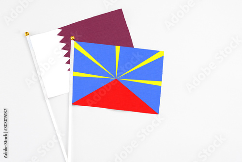 Reunion and Qatar stick flags on white background. High quality fabric, miniature national flag. Peaceful global concept.White floor for copy space.