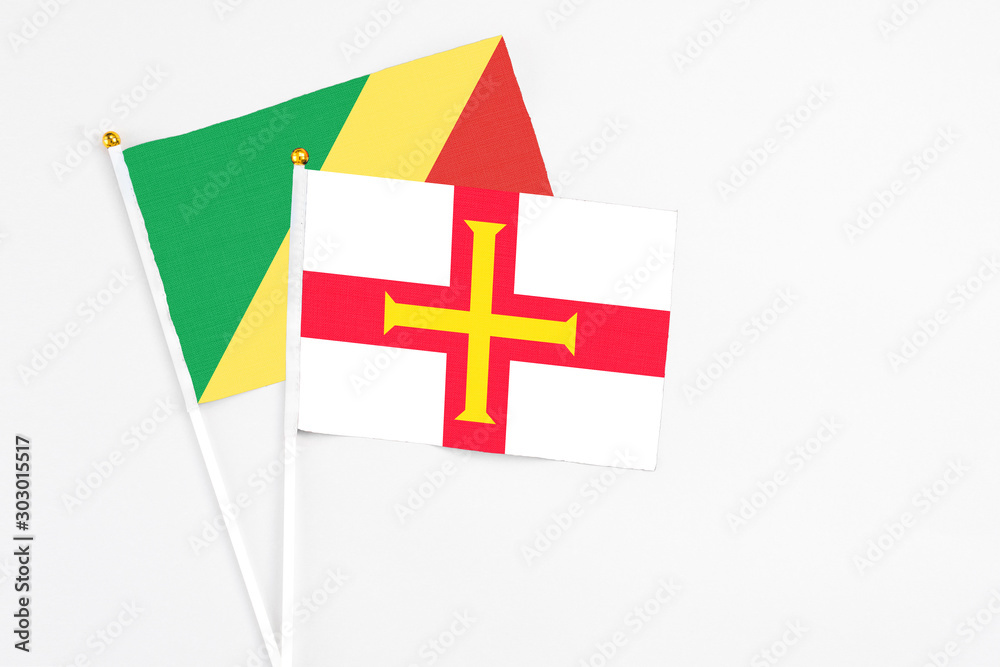 Guernsey and Republic Of The Congo stick flags on white background. High quality fabric, miniature national flag. Peaceful global concept.White floor for copy space.