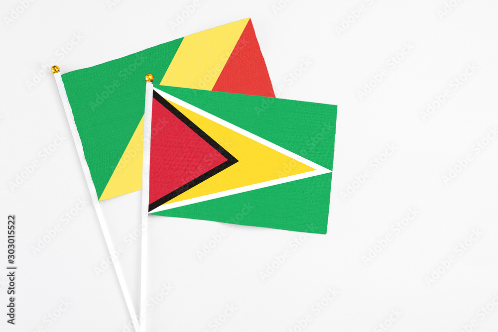 Obraz premium Guyana and Republic Of The Congo stick flags on white background. High quality fabric, miniature national flag. Peaceful global concept.White floor for copy space.