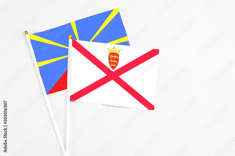 Jersey and Reunion stick flags on white background. High quality fabric, miniature national flag. Peaceful global concept.White floor for copy space.
