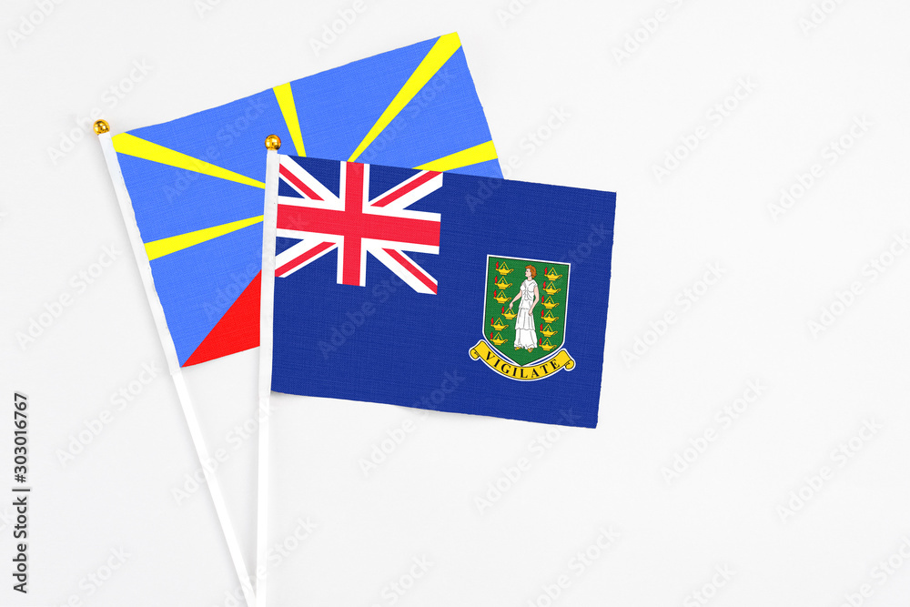 Fototapeta premium British Virgin Islands and Reunion stick flags on white background. High quality fabric, miniature national flag. Peaceful global concept.White floor for copy space.