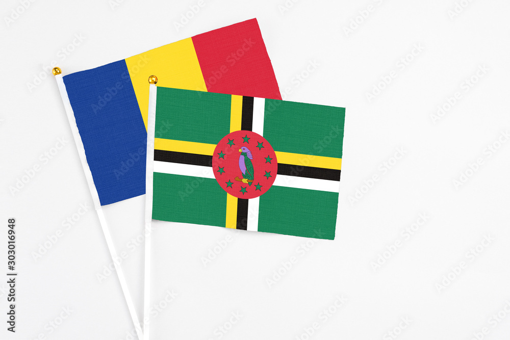 Fototapeta premium Dominica and Romania stick flags on white background. High quality fabric, miniature national flag. Peaceful global concept.White floor for copy space.