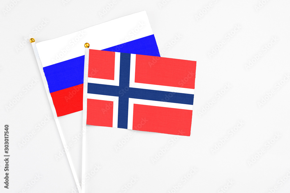 Bouvet Islands and Russia stick flags on white background. High quality fabric, miniature national flag. Peaceful global concept.White floor for copy space.