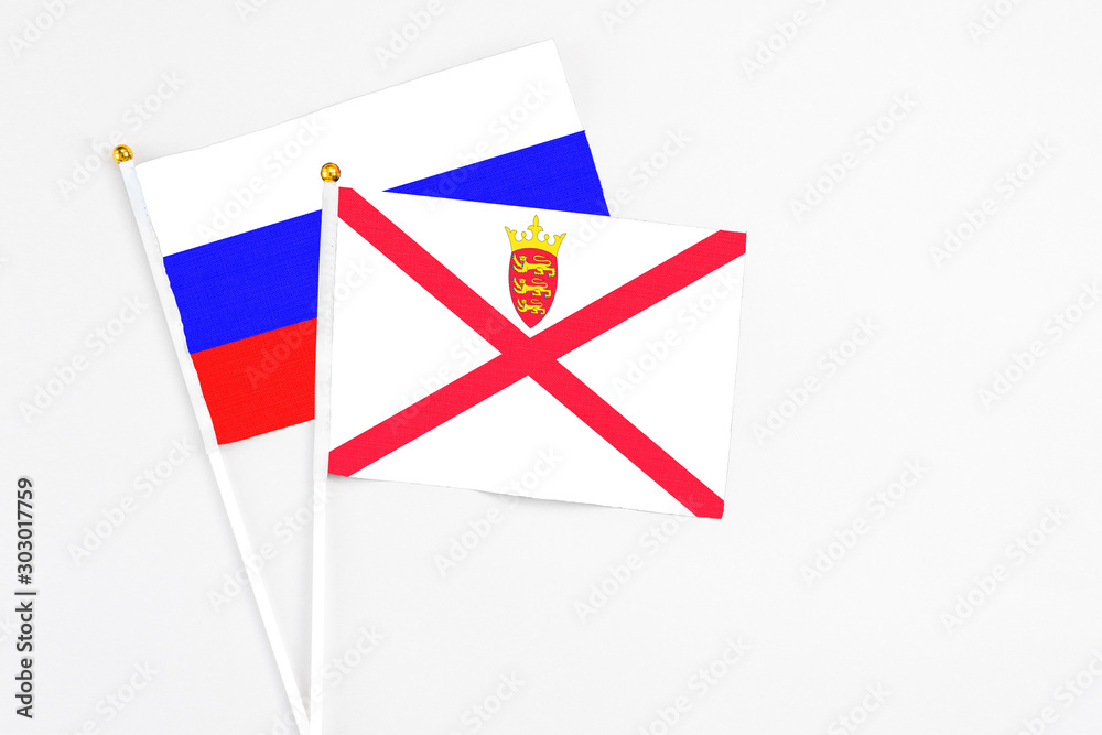 Jersey and Russia stick flags on white background. High quality fabric, miniature national flag. Peaceful global concept.White floor for copy space. Jersey and Russia stick flags on white background. High quality fabric, miniature national flag. Peaceful global concept.White floor for copy space.