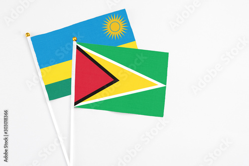 Guyana and Rwanda stick flags on white background. High quality fabric  miniature national flag. Peaceful global concept.White floor for copy space.