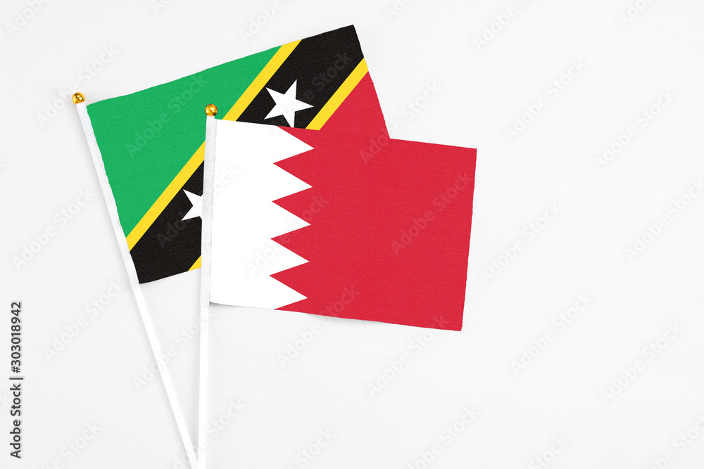Bahrain and Saint Kitts And Nevis stick flags on white background. High quality fabric, miniature national flag. Peaceful global concept.White floor for copy space.
