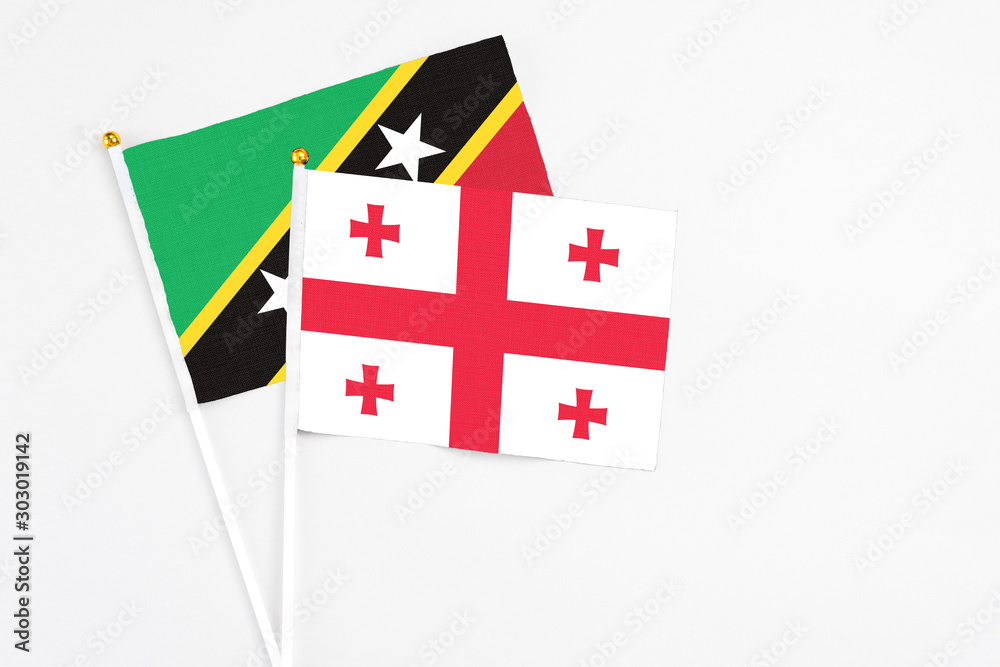 Georgia and Saint Kitts And Nevis stick flags on white background. High quality fabric, miniature national flag. Peaceful global concept.White floor for copy space.