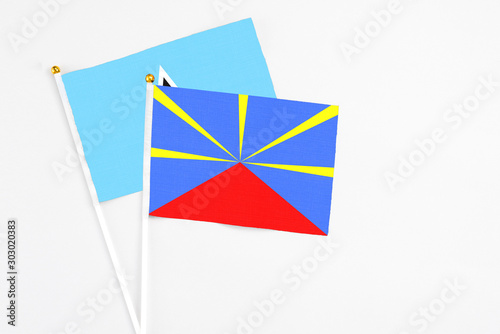 Reunion and Saint Lucia stick flags on white background. High quality fabric, miniature national flag. Peaceful global concept.White floor for copy space.