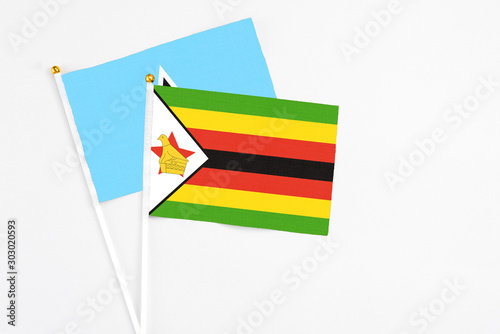 Zimbabwe and Saint Lucia stick flags on white background. High quality fabric  miniature national flag. Peaceful global concept.White floor for copy space.