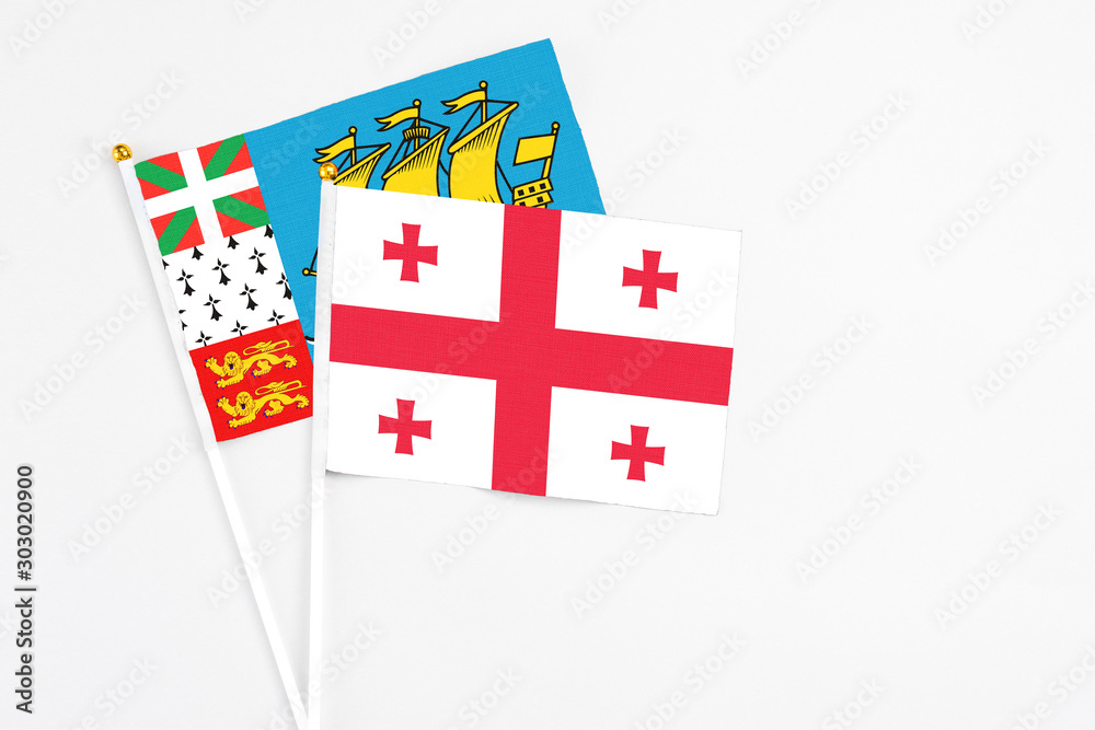 Georgia and Saint Pierre And Miquelon stick flags on white background. High quality fabric, miniature national flag. Peaceful global concept.White floor for copy space.