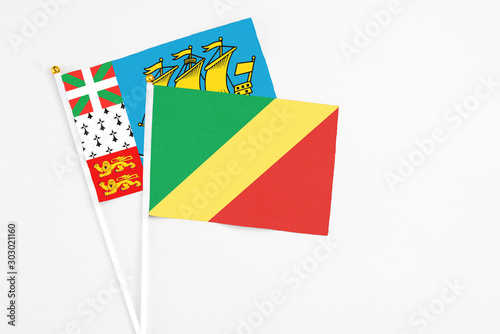 Republic Of The Congo and Saint Pierre And Miquelon stick flags on white background. High quality fabric, miniature national flag. Peaceful global concept.White floor for copy space. photo