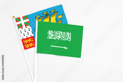 Saudi Arabia and Saint Pierre And Miquelon stick flags on white background. High quality fabric, miniature national flag. Peaceful global concept.White floor for copy space.