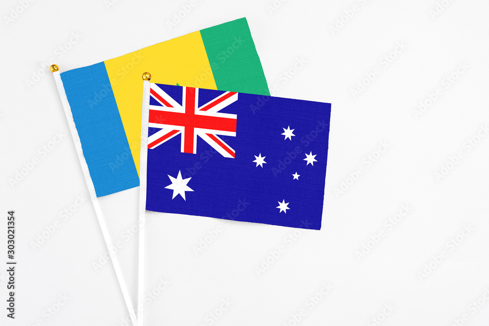 Fototapeta premium Australia and Saint Vincent And The Grenadines stick flags on white background. High quality fabric, miniature national flag. Peaceful global concept.White floor for copy space.