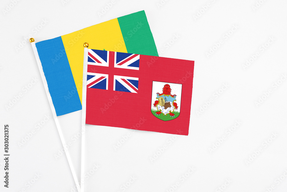 Bermuda and Saint Vincent And The Grenadines stick flags on white background. High quality fabric, miniature national flag. Peaceful global concept.White floor for copy space.