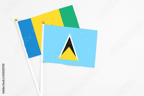 Free Download Saint Lucia and Saint Vincent And The Grenadines stick flags on white background. High quality fabric, miniature national flag. Peaceful global concept.White floor for copy space. - GFXLoad