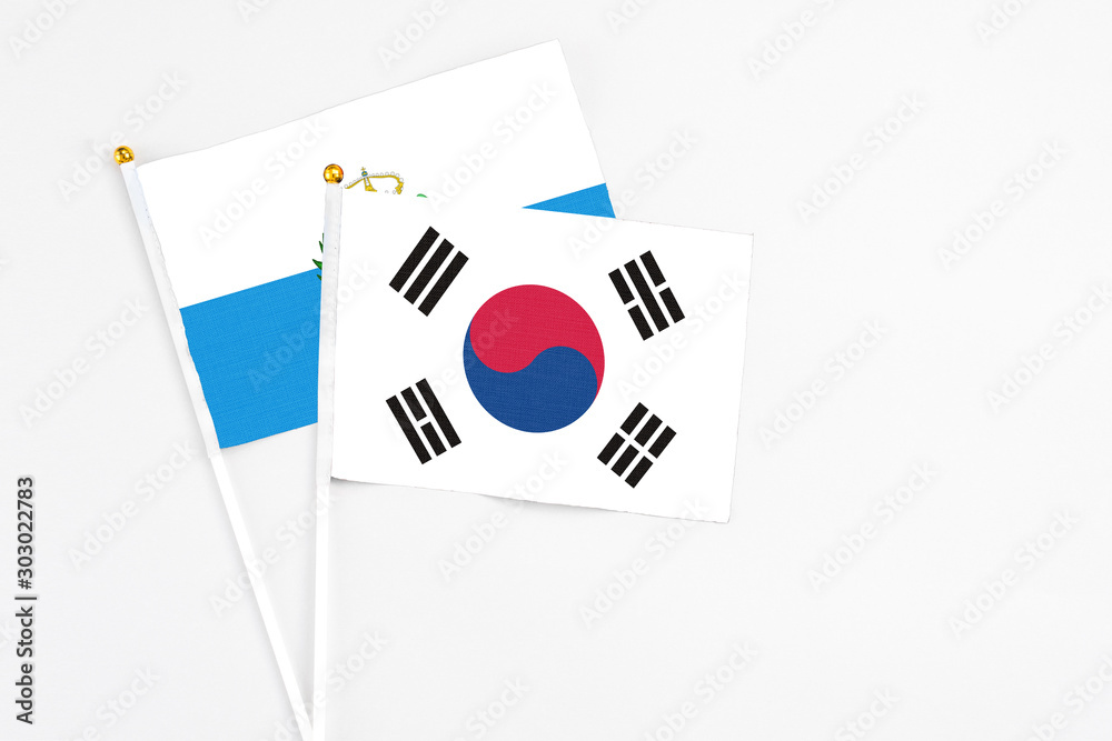 South Korea and San Marino stick flags on white background. High quality fabric, miniature national flag. Peaceful global concept.White floor for copy space.