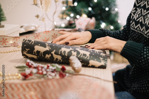 Woman wrapping gifts with deer paper for holidays
