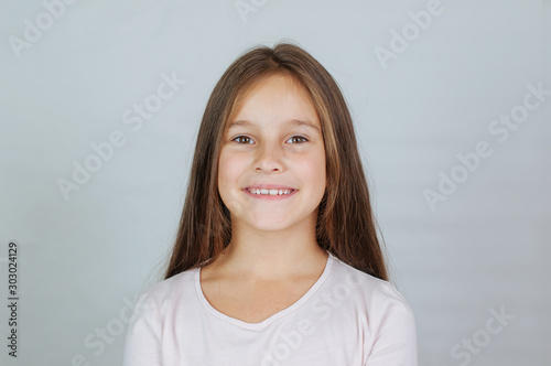 Little pretty girl age 6-7 years with very long hair expresses emotional joy and a smile on a white background