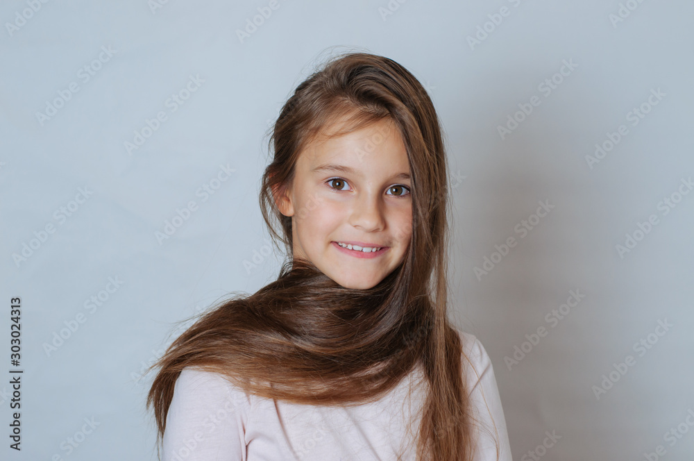 Little pretty girl age 6-7 years with very long hair expresses emotional joy and a smile on a white background