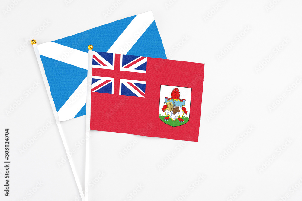 Fototapeta premium Bermuda and Scotland stick flags on white background. High quality fabric, miniature national flag. Peaceful global concept.White floor for copy space.