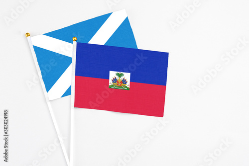 Haiti and Scotland stick flags on white background. High quality fabric, miniature national flag. Peaceful global concept.White floor for copy space.