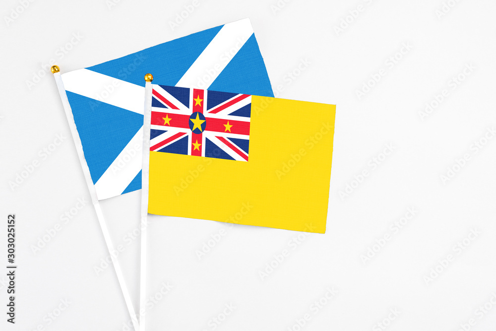 Niue and Scotland stick flags on white background. High quality fabric, miniature national flag. Peaceful global concept.White floor for copy space. Niue and Scotland stick flags on white background. High quality fabric, miniature national flag. Peaceful global concept.White floor for copy space.