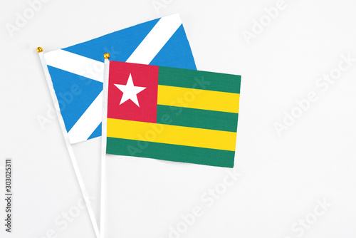 Togo and Scotland stick flags on white background. High quality fabric  miniature national flag. Peaceful global concept.White floor for copy space.