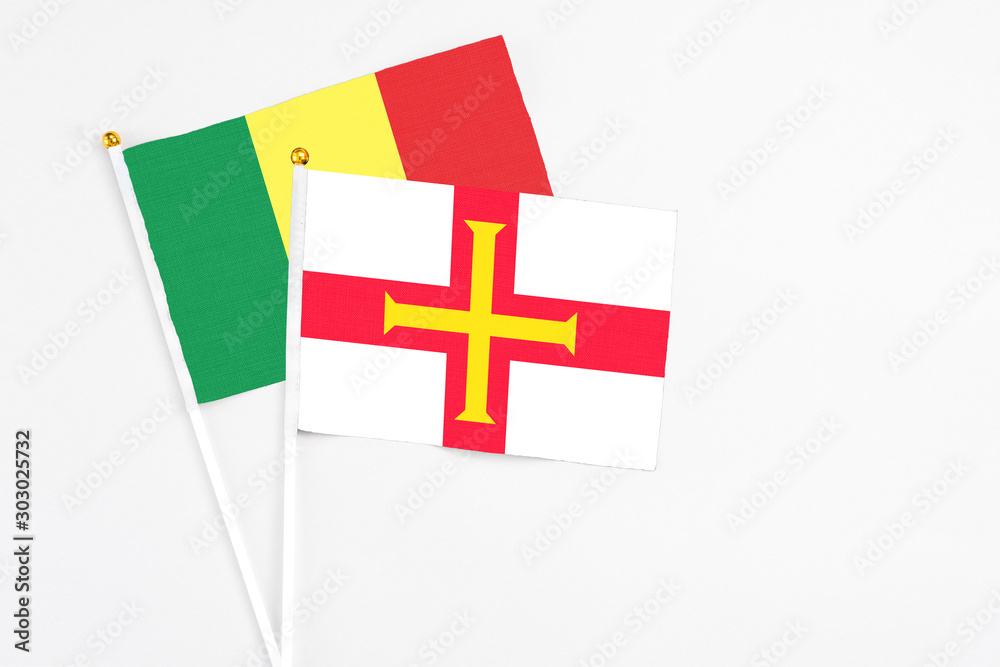Guernsey and Senegal stick flags on white background. High quality fabric, miniature national flag. Peaceful global concept.White floor for copy space.
