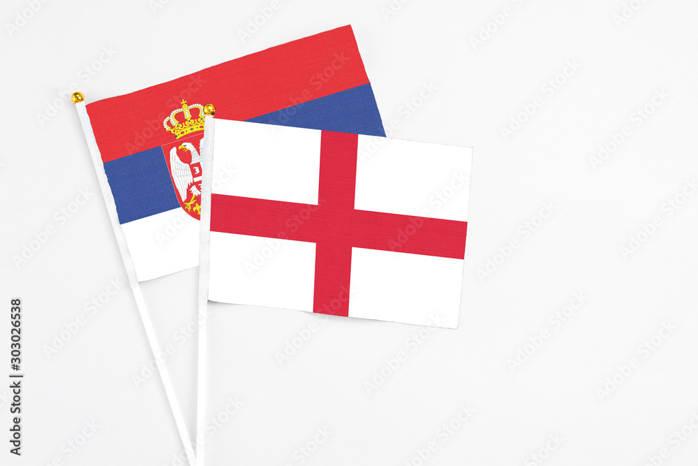 England and Serbia stick flags on white background. High quality fabric, miniature national flag. Peaceful global concept.White floor for copy space.