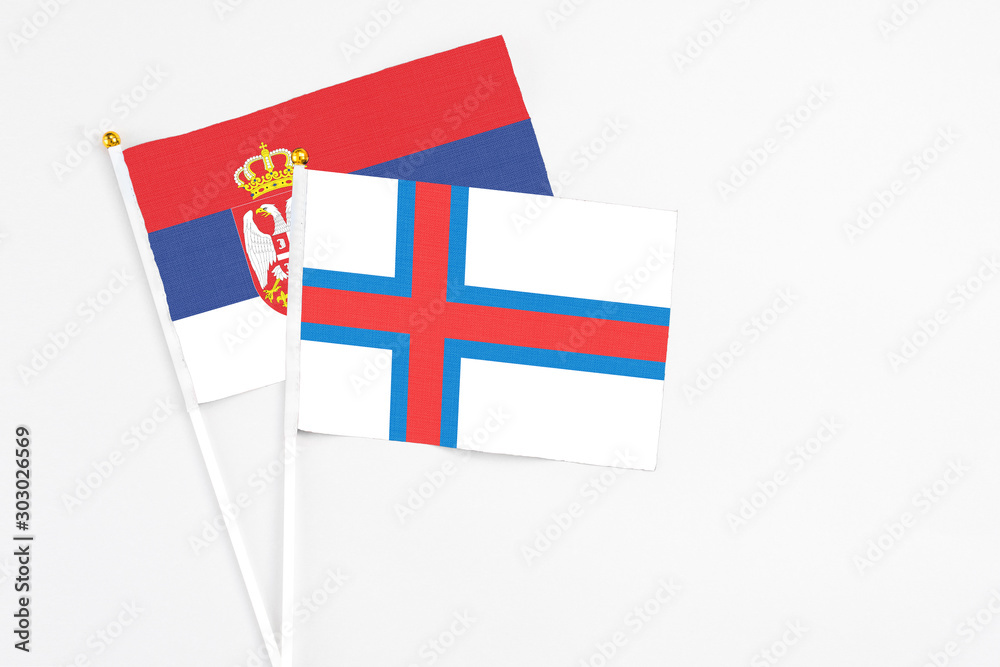 Faroe Islands and Serbia stick flags on white background. High quality fabric, miniature national flag. Peaceful global concept.White floor for copy space.