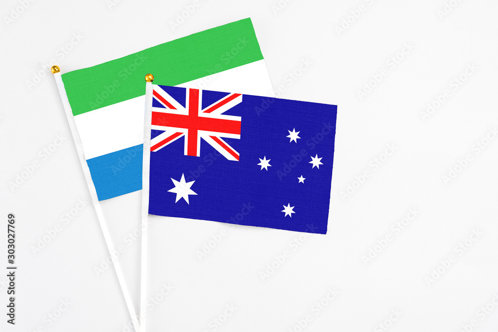 Fototapeta premium Australia and Sierra Leone stick flags on white background. High quality fabric, miniature national flag. Peaceful global concept.White floor for copy space.