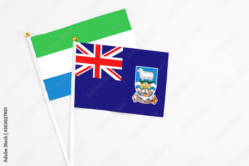 Fototapeta premium Falkland Islands and Sierra Leone stick flags on white background. High quality fabric, miniature national flag. Peaceful global concept.White floor for copy space.