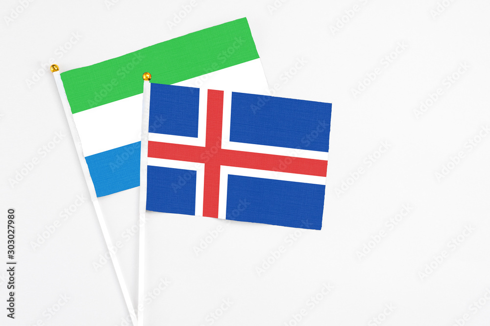Iceland and Sierra Leone stick flags on white background. High quality fabric, miniature national flag. Peaceful global concept.White floor for copy space.