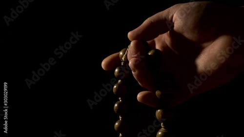 Hand with beads against black background - Eastern rosary with incense smoke photo