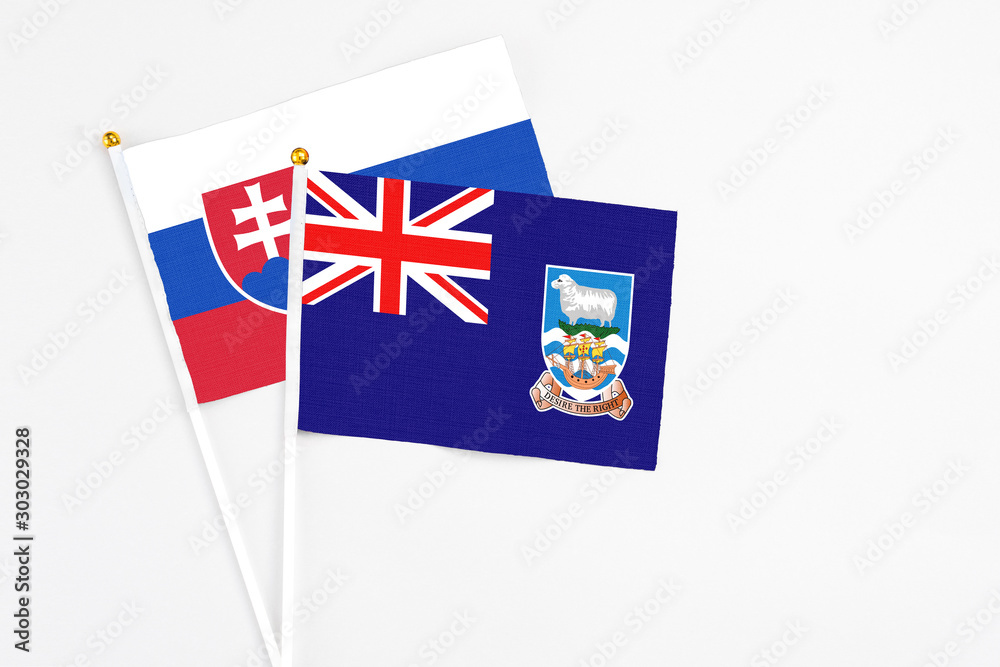 Fototapeta premium Falkland Islands and Slovakia stick flags on white background. High quality fabric, miniature national flag. Peaceful global concept.White floor for copy space.