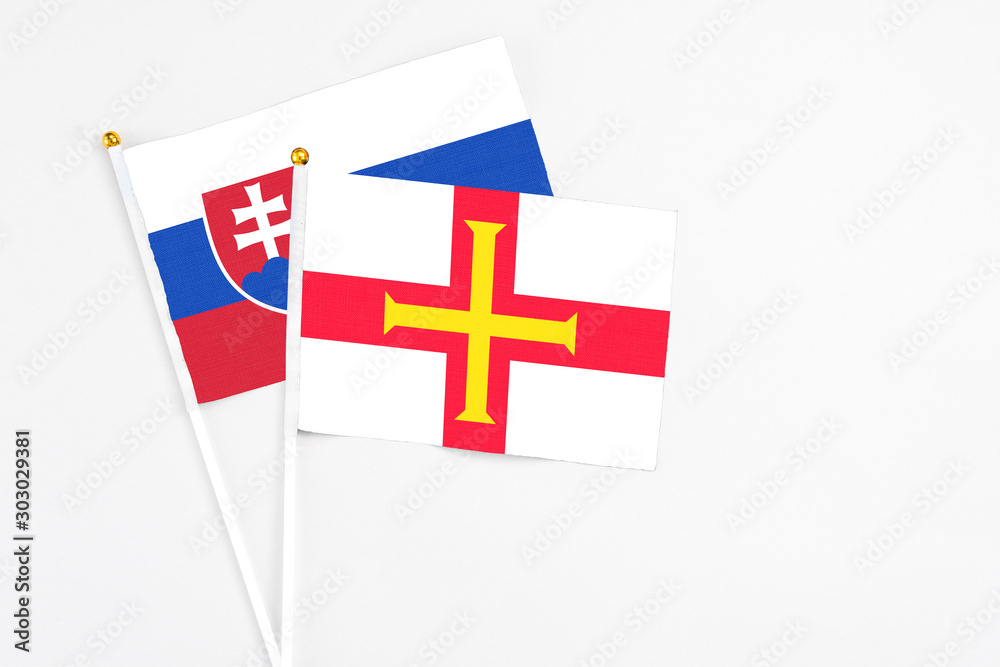 Guernsey and Slovakia stick flags on white background. High quality fabric, miniature national flag. Peaceful global concept.White floor for copy space.