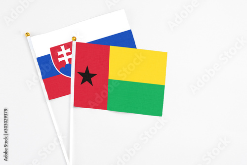 Guinea Bissau and Slovakia stick flags on white background. High quality fabric, miniature national flag. Peaceful global concept.White floor for copy space.