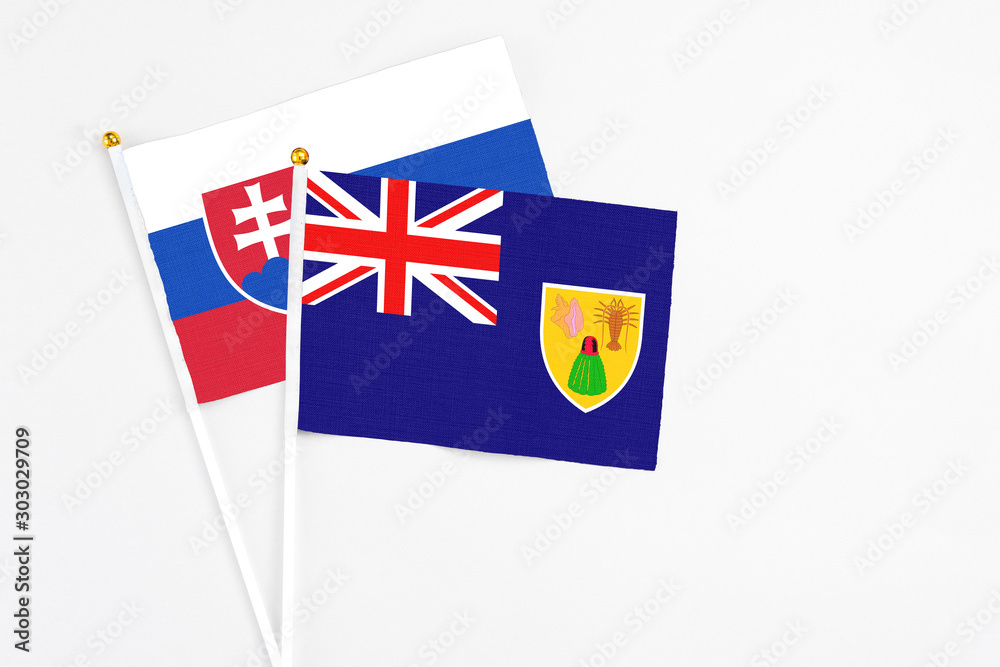 Fototapeta premium Turks And Caicos Islands and Slovakia stick flags on white background. High quality fabric, miniature national flag. Peaceful global concept.White floor for copy space.