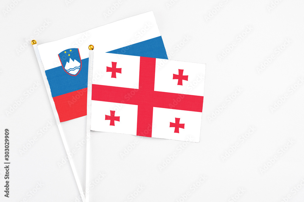 Georgia and Slovenia stick flags on white background. High quality fabric, miniature national flag. Peaceful global concept.White floor for copy space.