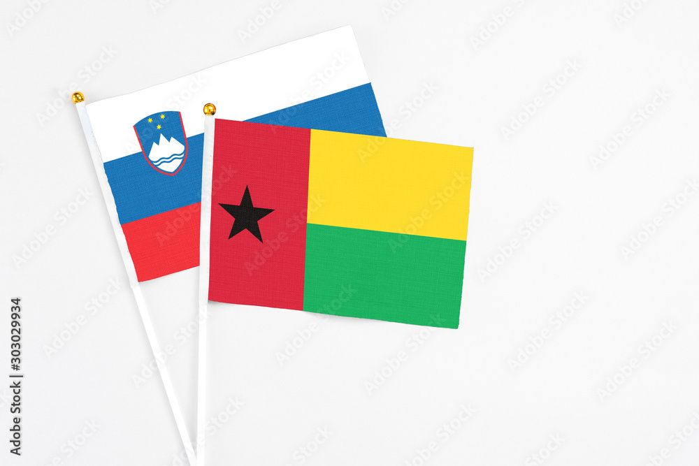 Guinea Bissau and Slovenia stick flags on white background. High quality fabric, miniature national flag. Peaceful global concept.White floor for copy space. Guinea Bissau and Slovenia stick flags on white background. High quality fabric, miniature national flag. Peaceful global concept.White floor for copy space.