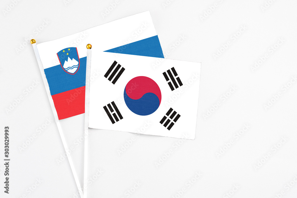 South Korea and Slovenia stick flags on white background. High quality fabric, miniature national flag. Peaceful global concept.White floor for copy space.
